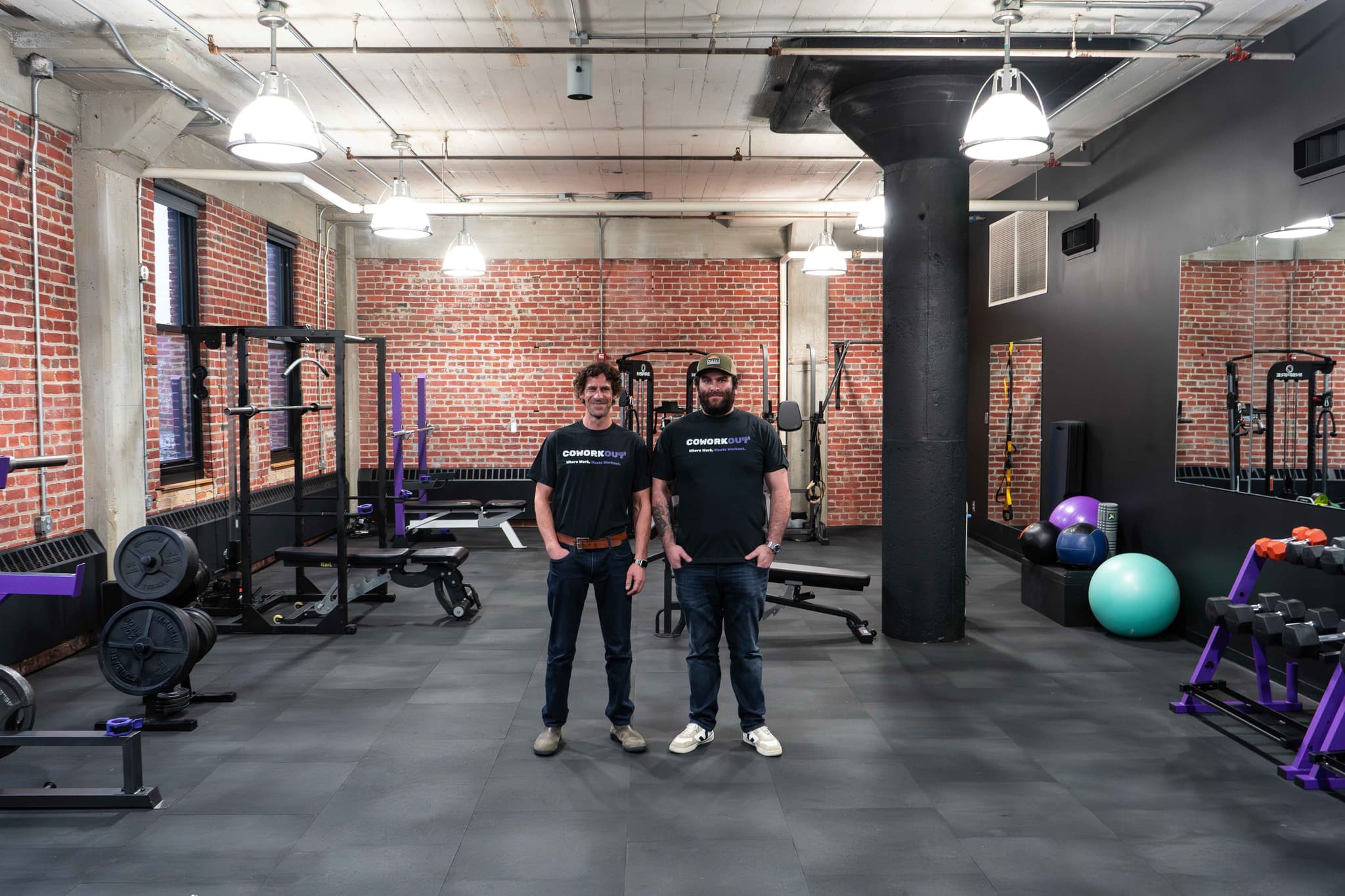 Founders of CoWorkout standing in the gym space at Elevator’s downtown Omaha location, surrounded by premium fitness equipment.